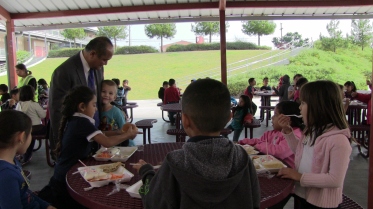 It takes Principal Godwin Higa a while to walk through the lunch courtyard. Every few steps, a child runs up to talk with him. 